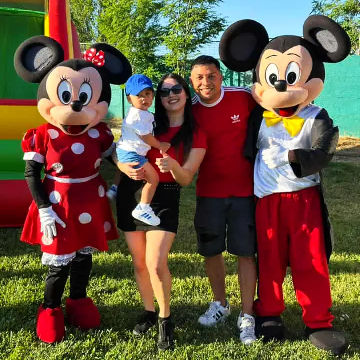 Mickey y Minnie con una familia en una fiesta al aire libre